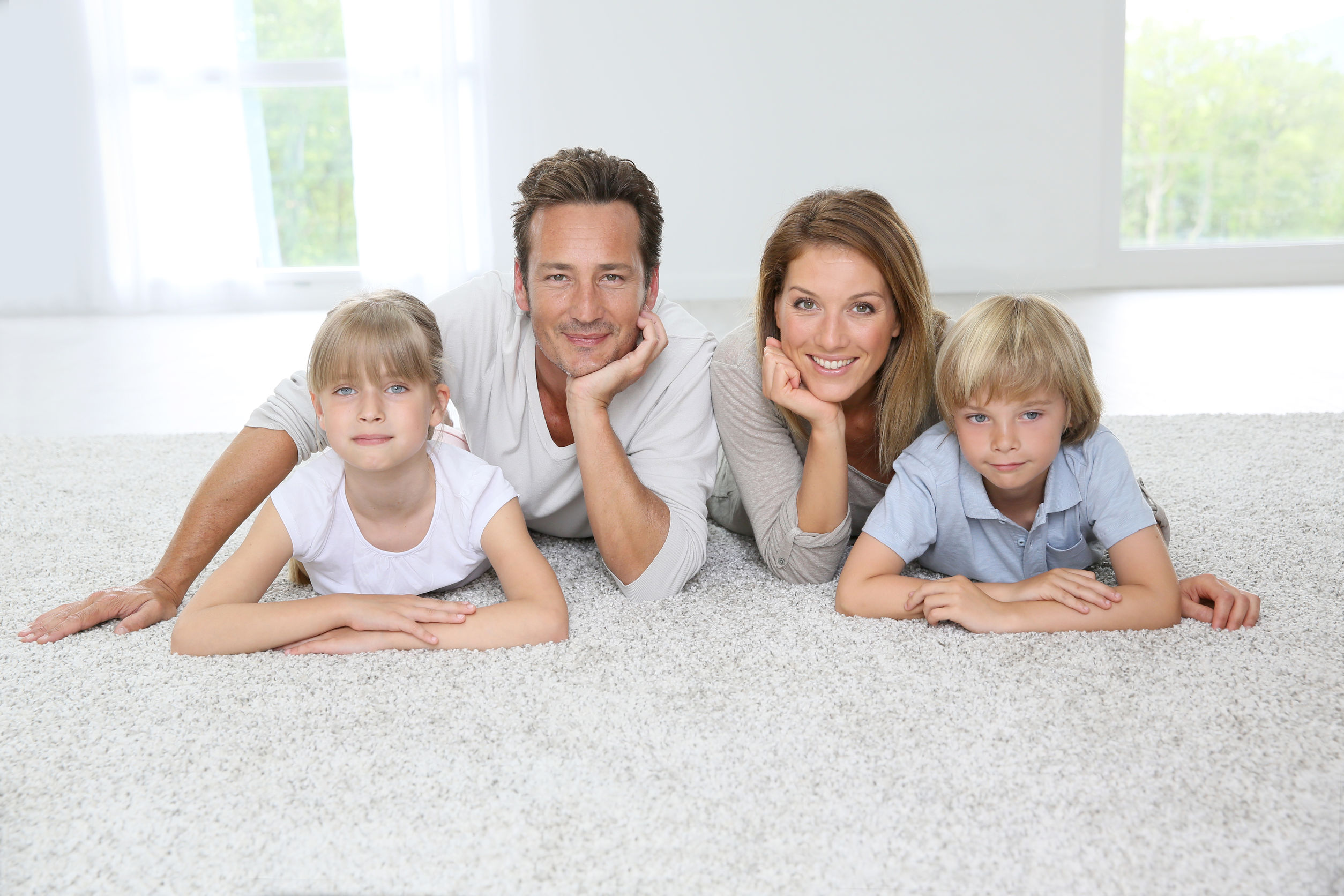 Happy family of four laying on carpet at home